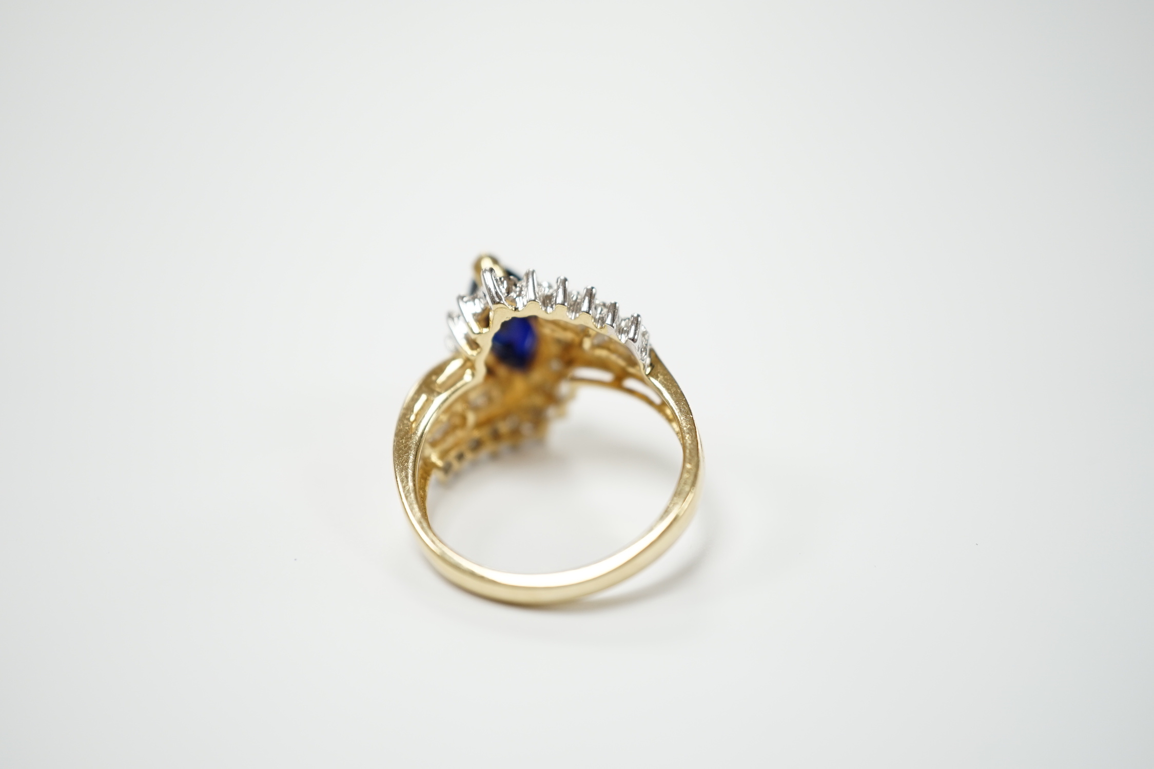 A modern 14k and single stone marquise cut sapphire and diamond chip cluster set crossover dress ring, size M, gross weight 5.3 grams.